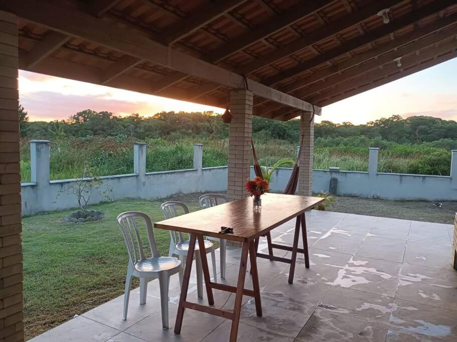 una mesa de madera y sillas en un patio en Casa em São Francisco do Sul, Praia do Ervino, en São Francisco do Sul