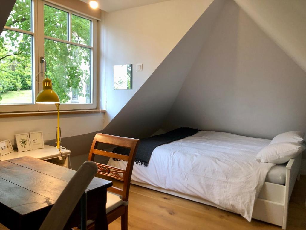een slaapkamer met een bed, een tafel en een raam bij Genval-BNB-Lake in Genval