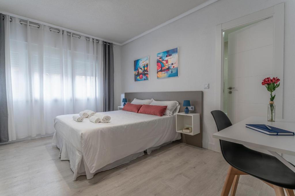 Un dormitorio con una cama con sábanas blancas y almohadas rojas. en Hotel Gabriel y Galán, en Salamanca