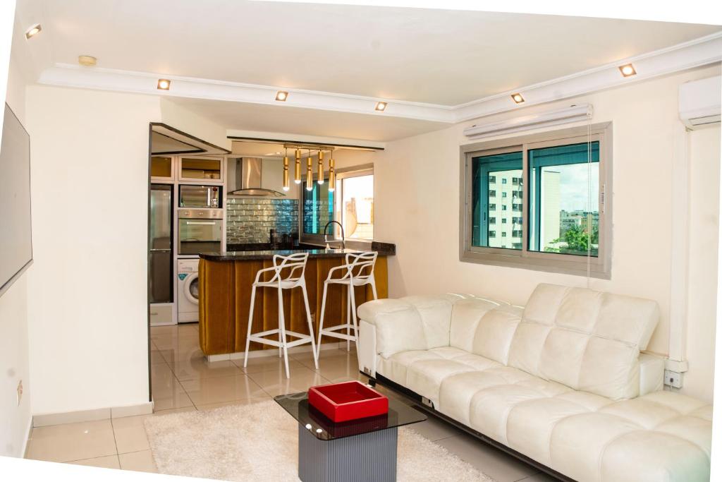 a living room with a white couch and a kitchen at Villa Princess Douala Bali in Douala