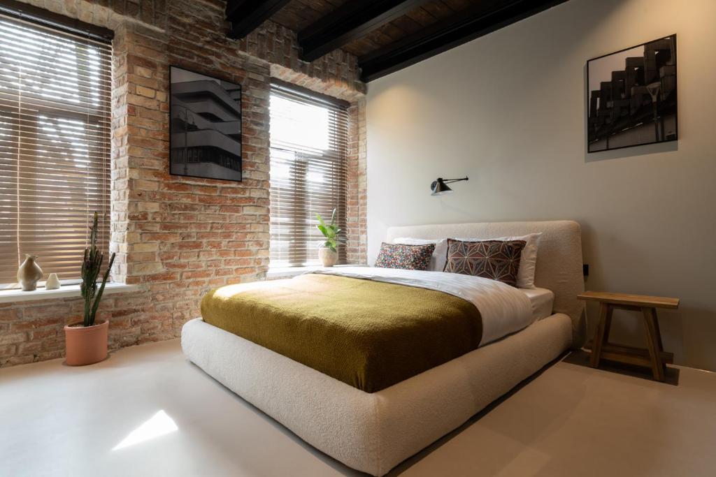 une chambre avec un lit et un mur de briques dans l'établissement Hortus Vilnius, à Vilnius