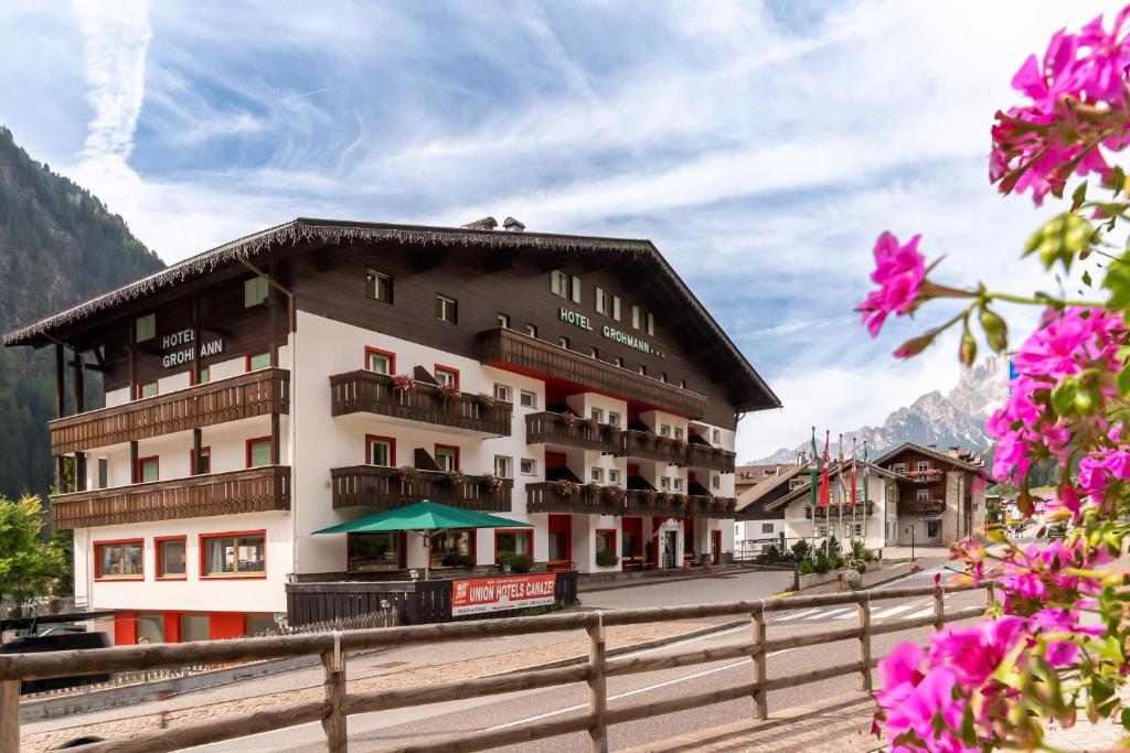 a hotel in the mountains with pink flowers at Hotel Grohmann in Campitello di Fassa