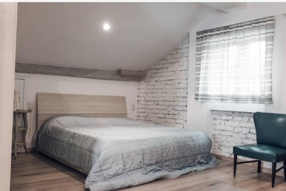 Mansarda Pascoli في Malnate: غرفة نوم بسرير كبير وكرسي ازرق