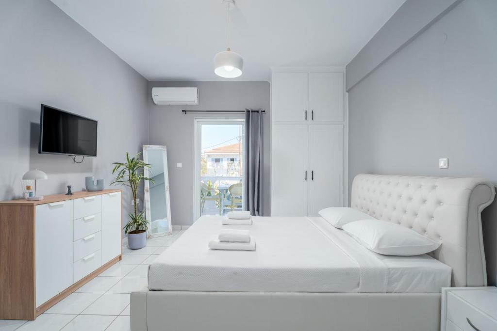 1 dormitorio blanco con 1 cama y TV en Casa Albastra Rooms & Suites en Porto Heli