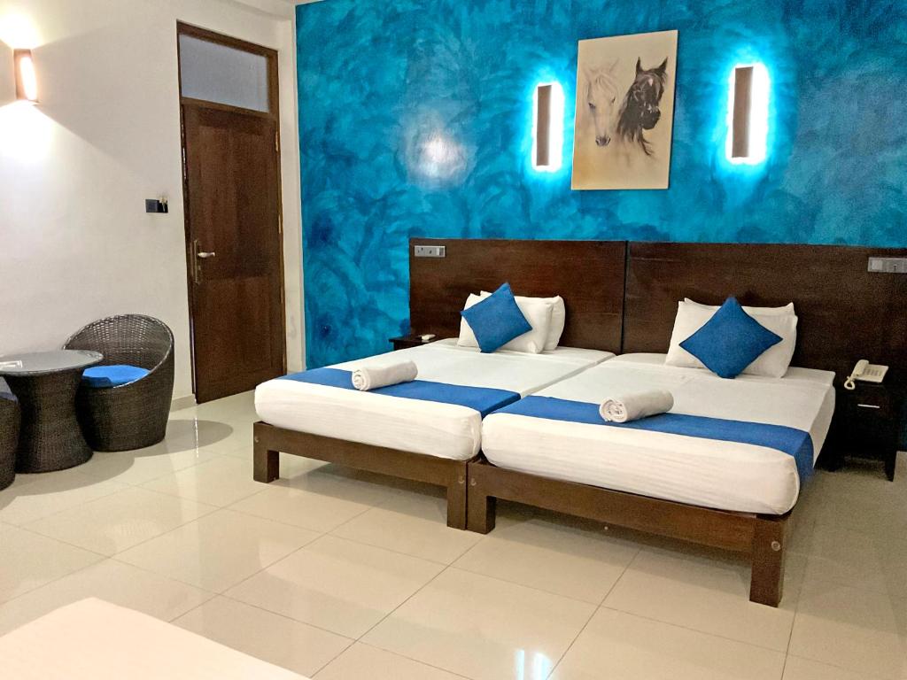 um quarto com uma cama grande e paredes azuis em Grand Detagamuwa em Kataragama