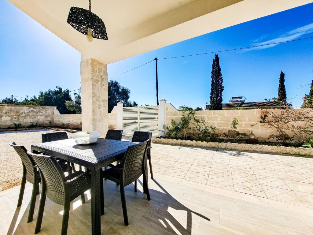 Una mesa de comedor y sillas en un patio. en VILLA per vacanza relax Salento Puglia, en San Pietro in Bevagna