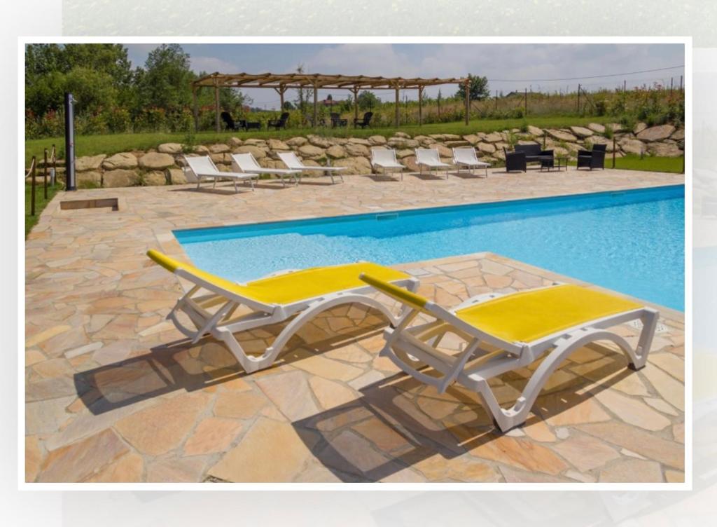 een paar ligstoelen naast een zwembad bij Tenuta Costa dei platani, casa dei platani in Acqui Terme