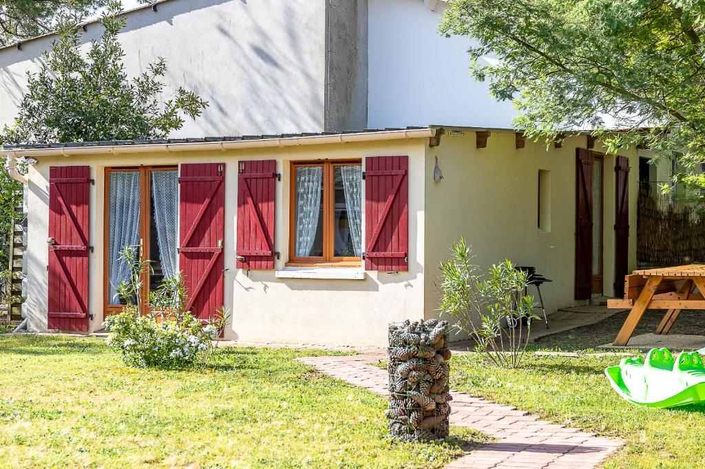 une petite maison avec des fenêtres rouges et une table dans l'établissement Entre plages à 2kms et forêt, à Saint-Jean-de-Monts