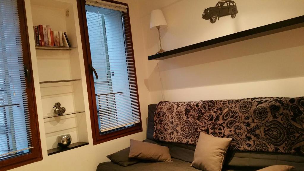 ein Wohnzimmer mit einem Sofa und 2 Fenstern in der Unterkunft BEAU STUDIO CLIMATISE PROXIMITE PORTS ET PLAGES in La Ciotat