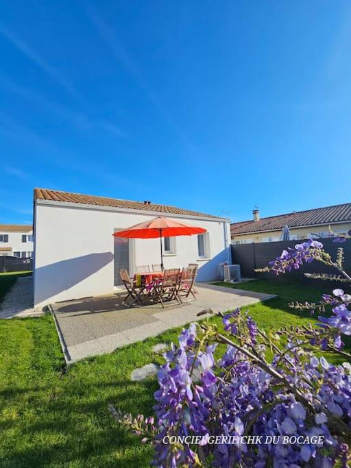 d'une terrasse avec une table et un parasol rouge. dans l'établissement Chez Tina jolie maison à 12 min du Puy du Fou, aux Herbiers