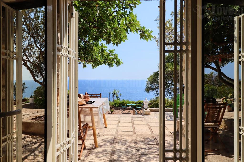 eine offene Tür zu einer Terrasse mit Meerblick in der Unterkunft La Casa del Pittore in Gagliano del Capo