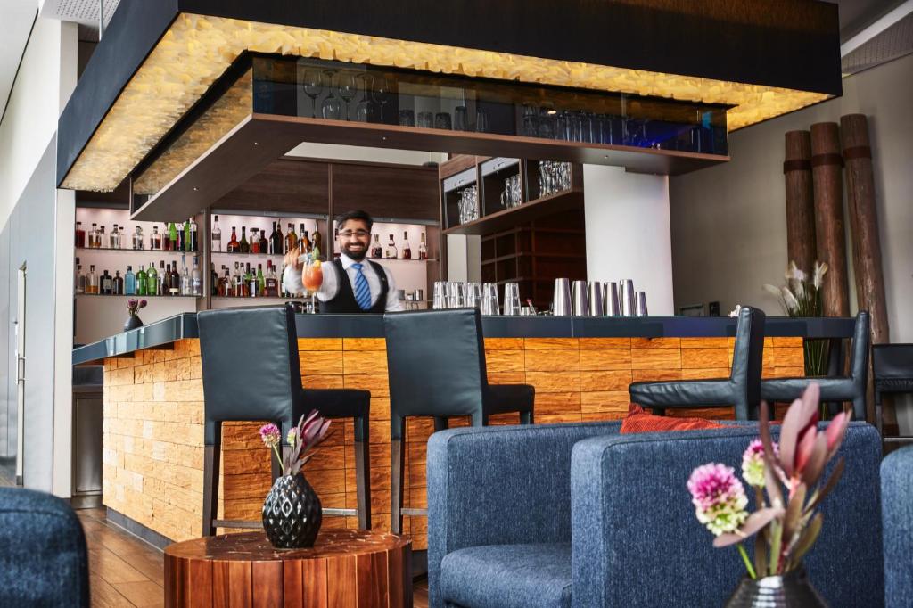 a man standing behind a bar in a restaurant at Steigenberger Hotel Bremen in Bremen