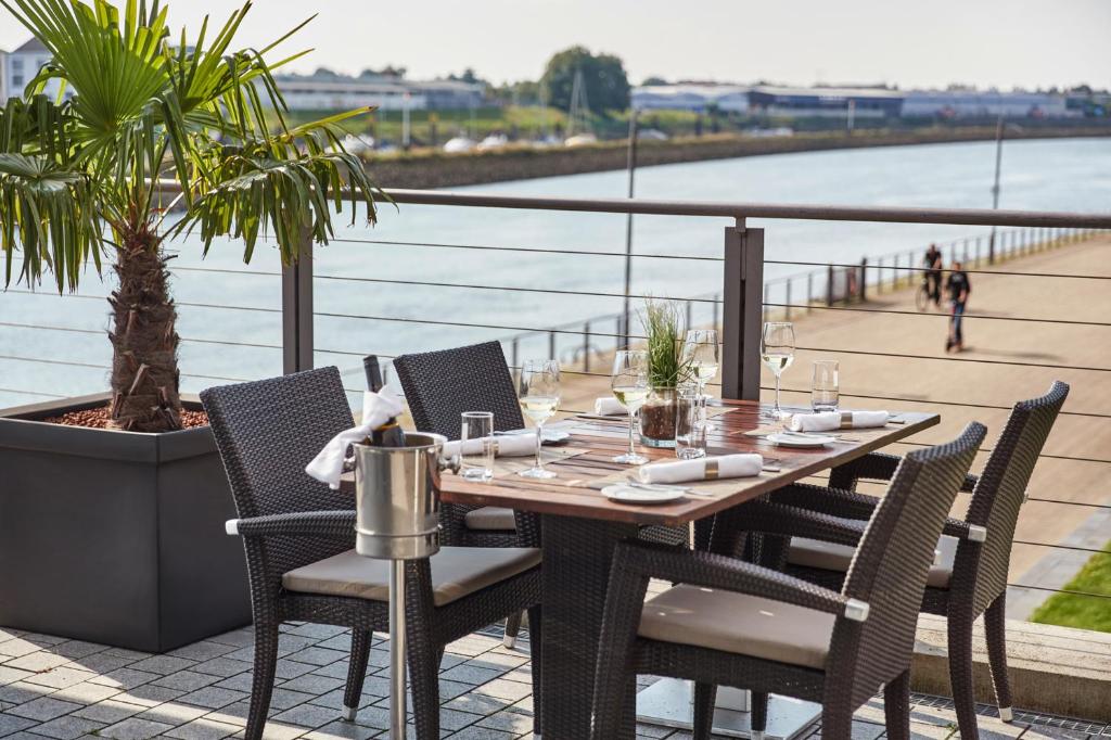 a table and chairs on a patio with a view of the water at Steigenberger Hotel Bremen in Bremen