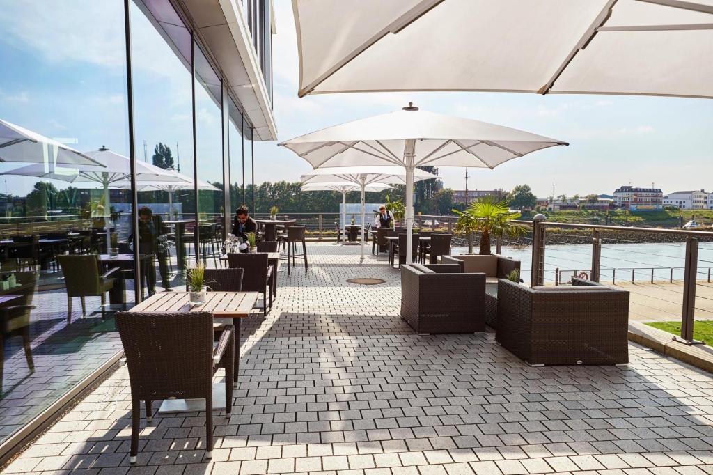 a restaurant with tables and chairs and umbrellas at Steigenberger Hotel Bremen in Bremen