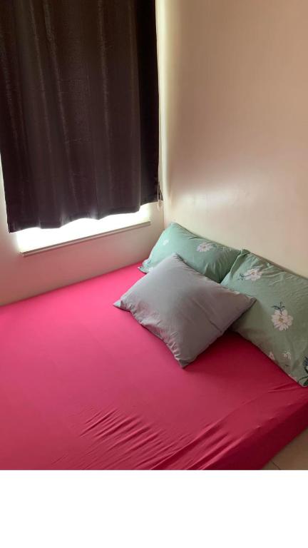 uma cama com duas almofadas sentadas num lençol vermelho em Abiah's Sweet Home em Manila