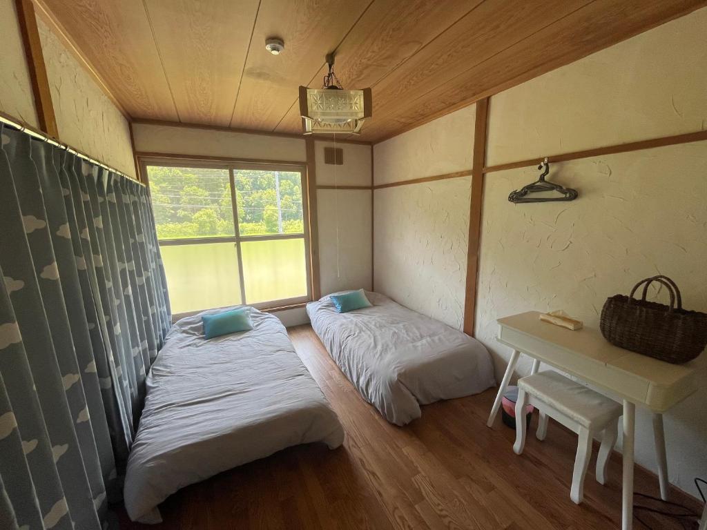 een kamer met 2 bedden, een tafel en een raam bij SOUND GARDEN 美瑛 River in Biei