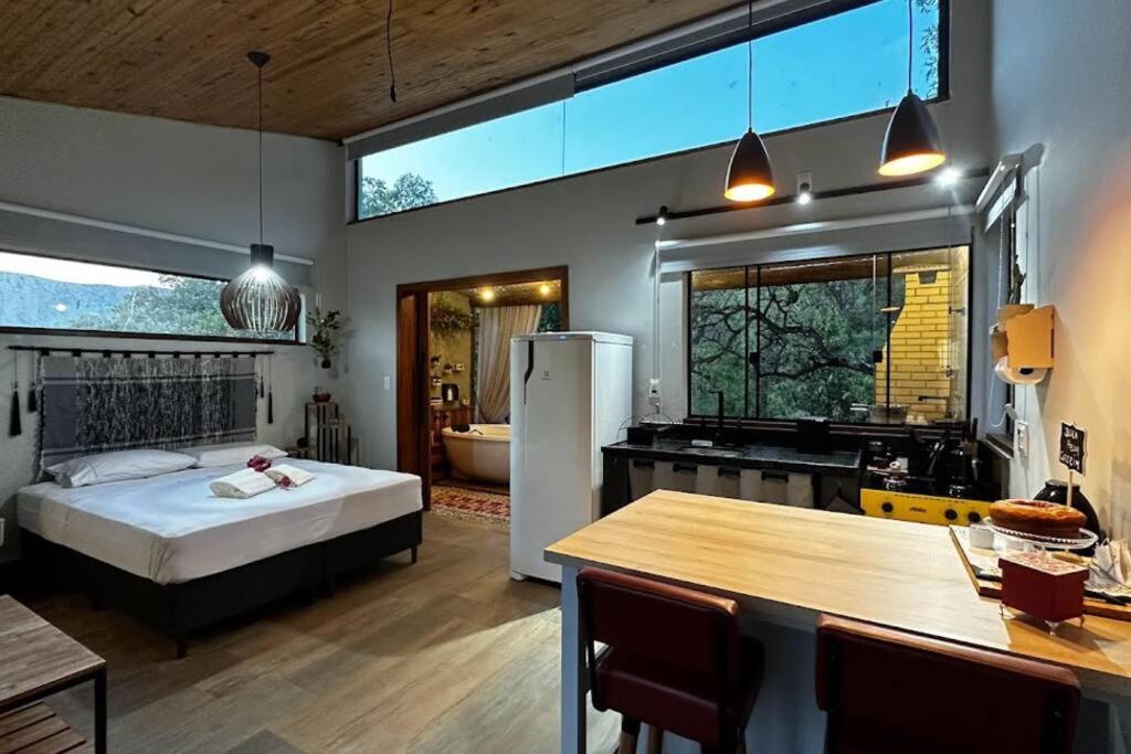 Cabanas da Mata - Cabana Candeia - Casa Branca/MG في كازا برانكا: غرفة نوم مع سرير ومطبخ مع حوض استحمام