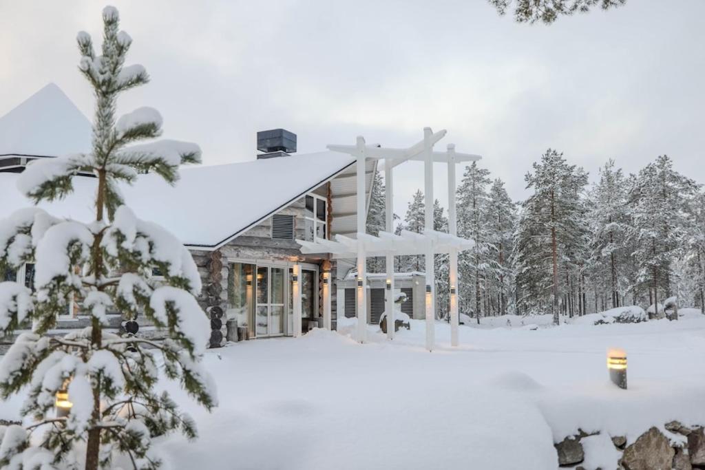 uma casa coberta de neve na floresta em HUNURIJÄRVI RESORT***** em Härmä