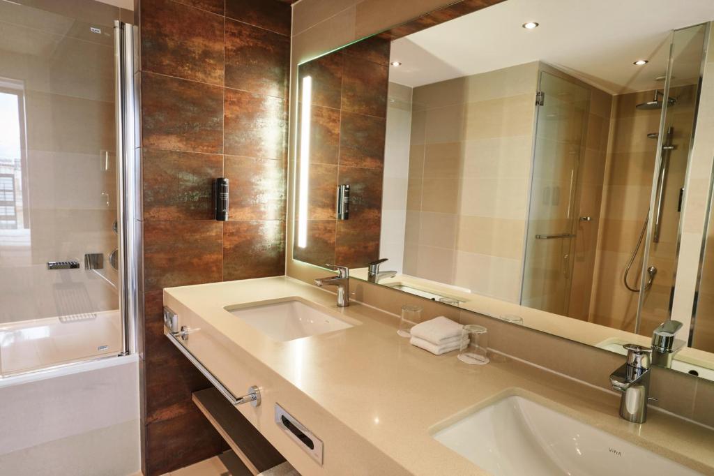 a bathroom with two sinks and a large mirror at Steigenberger Hotel Bremen in Bremen