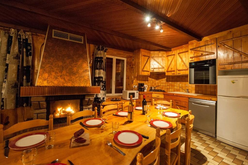 a kitchen with a wooden table and a fireplace at La Ruche in La Bresse