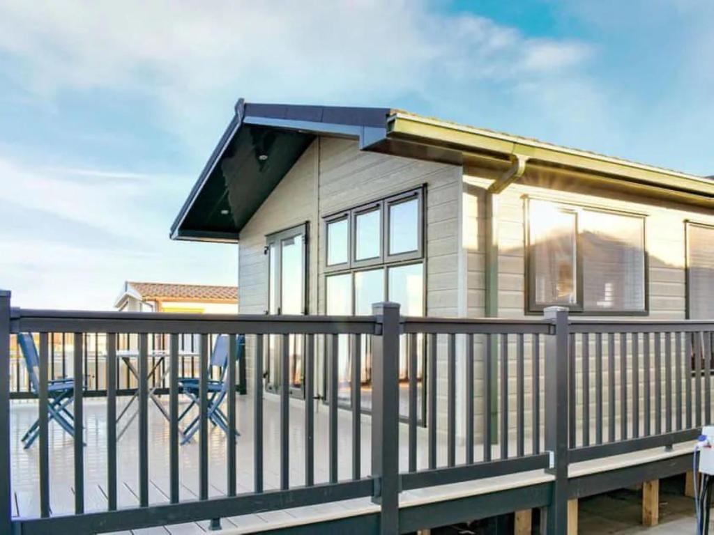 a small house with a railing on a deck at Victory Lodge 2 Bedroom - Sleeps 6 - Bron-Y-Wendon Holiday Park in Llanddulas