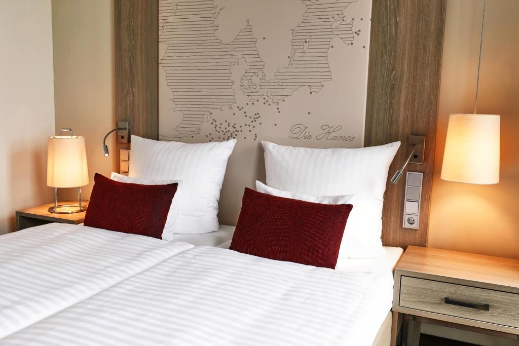 a bedroom with a bed with two red pillows at Steigenberger Hotel Bremen in Bremen