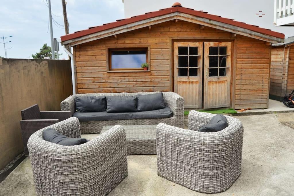 three wicker chairs and a couch in front of a building at La cabane de Robinson à 500m de la plage in Lacanau