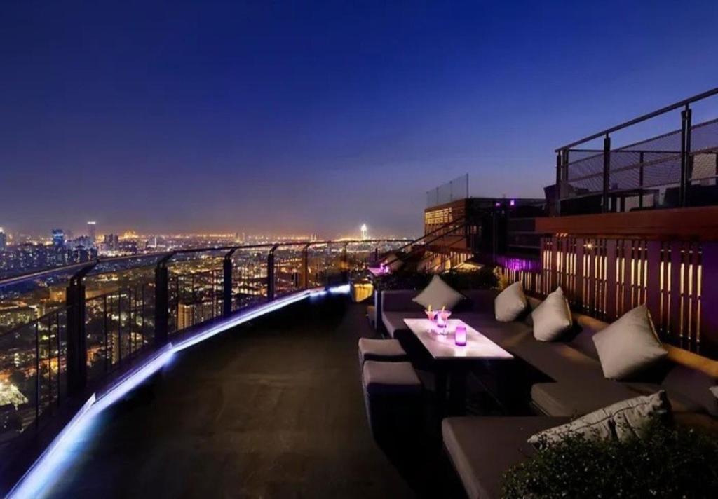 a balcony with couches on a building at night at Sathorn Prime Residence & Rooftop Sky Bar in Bangkok