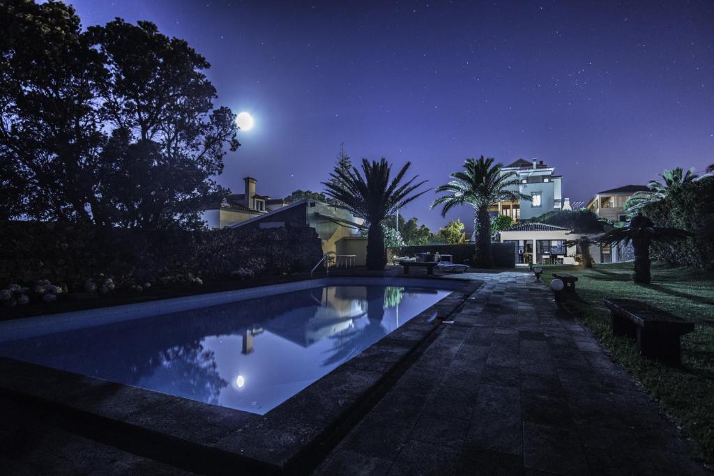 una piscina por la noche con la luna en el cielo en Casa do Cerco, en Água de Pau
