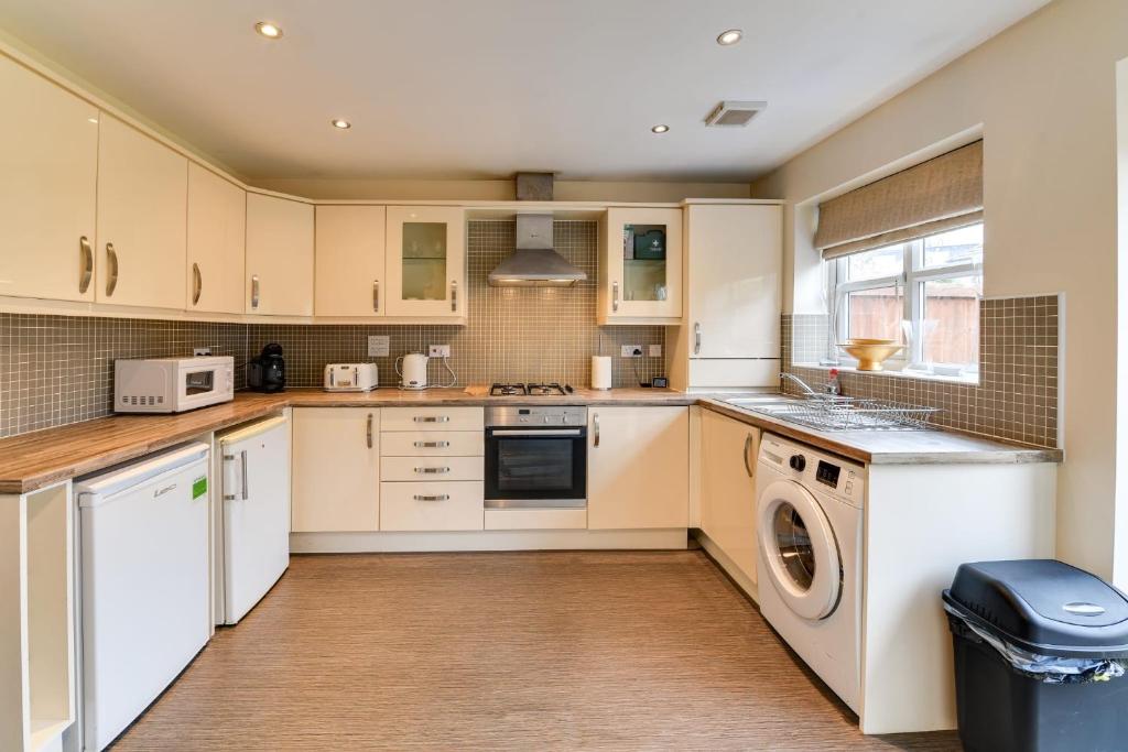 a kitchen with white cabinets and a washer and dryer at Charming 2-Bed House in Middleton Manchester in Manchester
