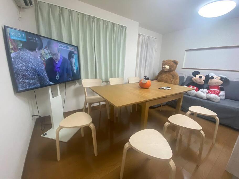 uma sala de estar com uma televisão e uma mesa e cadeiras em TOKYO池袋家族連れ4DKの子供連れ５星　 em Tóquio