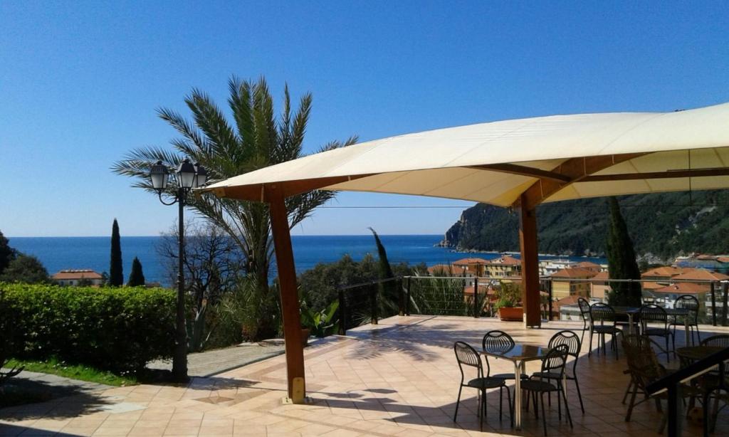 a patio with tables and chairs under a large umbrella at Agriturismo Villa Bardi struttura con camere vista mare in Riva Trigoso