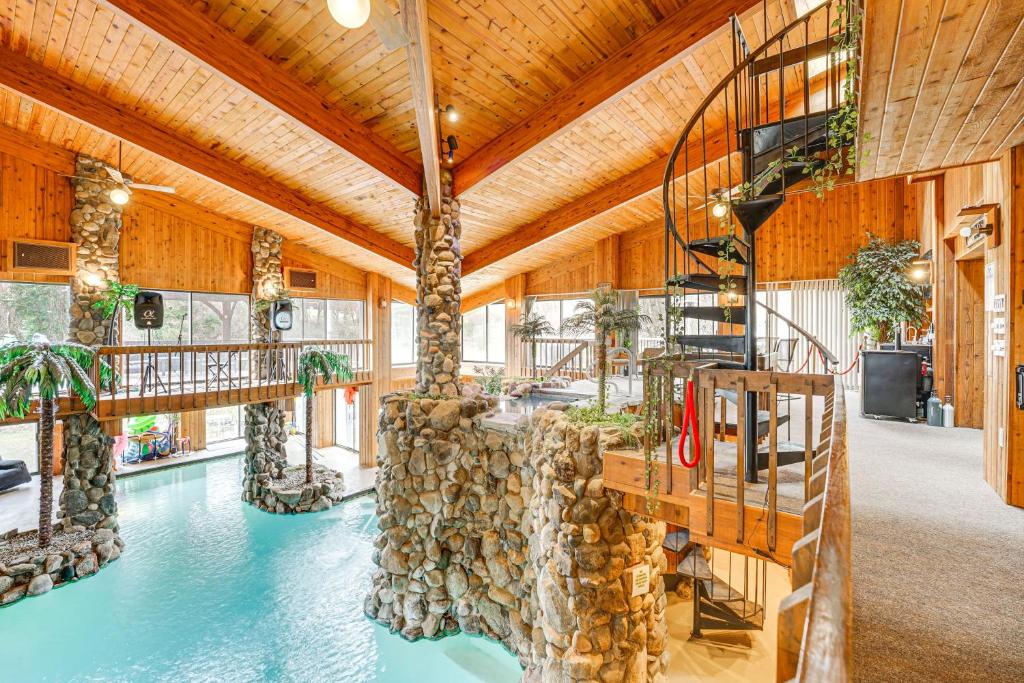 a room with a swimming pool with a fire escape and a staircase at Bloomfield Retreat with Indoor Pool and Tennis Court! in Bloomfield Hills
