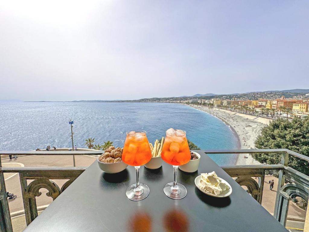 deux boissons sur une table avec vue sur une plage dans l'établissement Exceptional Sea Front Suite Nice France, à Nice