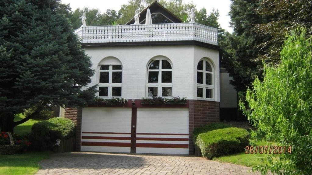 una casa blanca con una puerta y un garaje en Schöne Ferienwohnung am Wald gelegen mit großem Sonnenbalkon, 