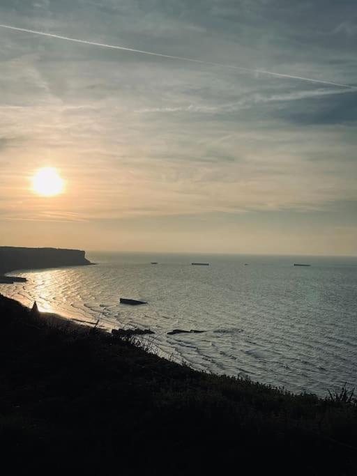un coucher de soleil sur l'océan avec des bateaux dans l'eau dans l'établissement Maison de famille au coeur d’Asnelles plage à 500m, à Asnelles