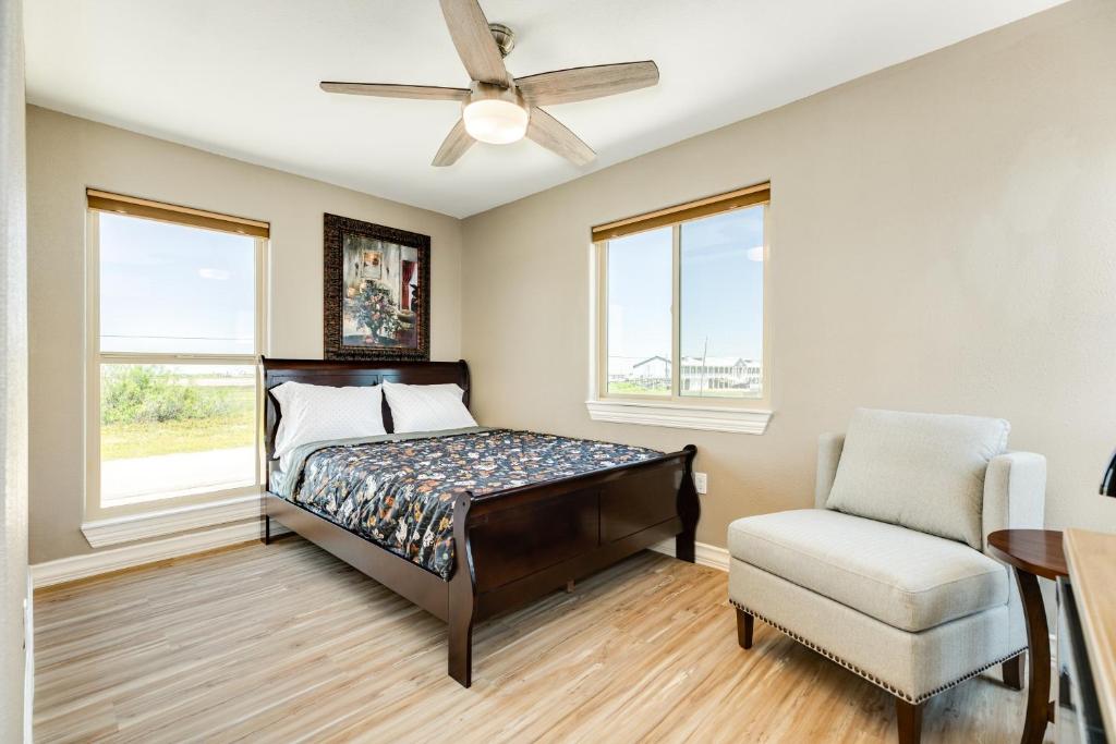 a bedroom with a bed and a chair and windows at Beach & Bay Views - Unit 2 - Bluewater Beach House in Surfside Beach