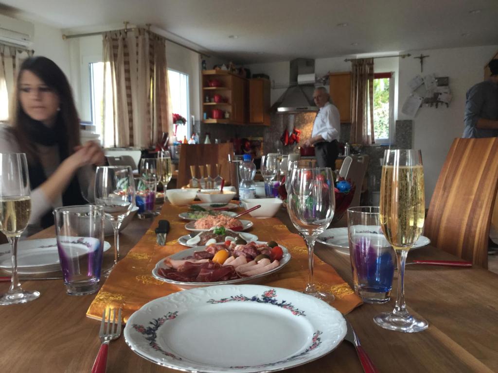 einen Tisch mit einem Teller mit Speisen und Weingläsern in der Unterkunft Haus Babić in Osijek