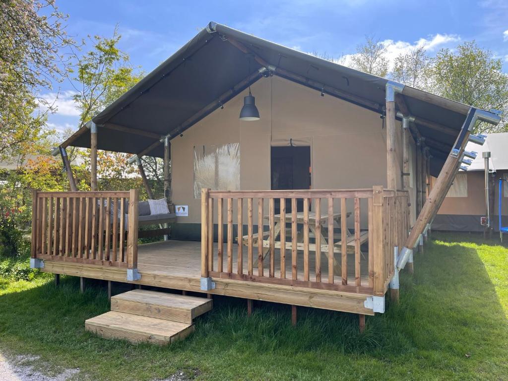 a house with a black roof and a deck at Safari Lodge Grou, luxe kamperen op een eiland! in Grou