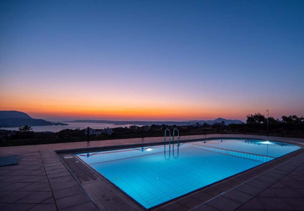 a swimming pool with a sunset in the background at Leyenia Serenity Houses in Kókkinon Khoríon