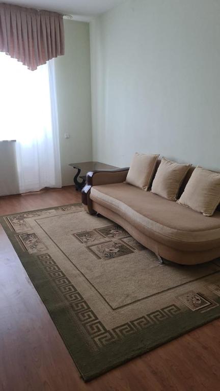 un canapé assis dans un salon avec un tapis dans l'établissement Студия в центре, à Astana