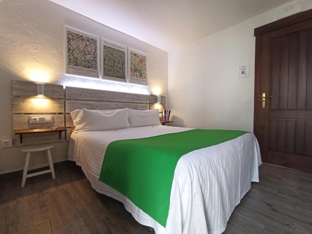 Un dormitorio con una cama verde y blanca y un escritorio en Casa Hotel LA JARANA, en Zahara de la Sierra