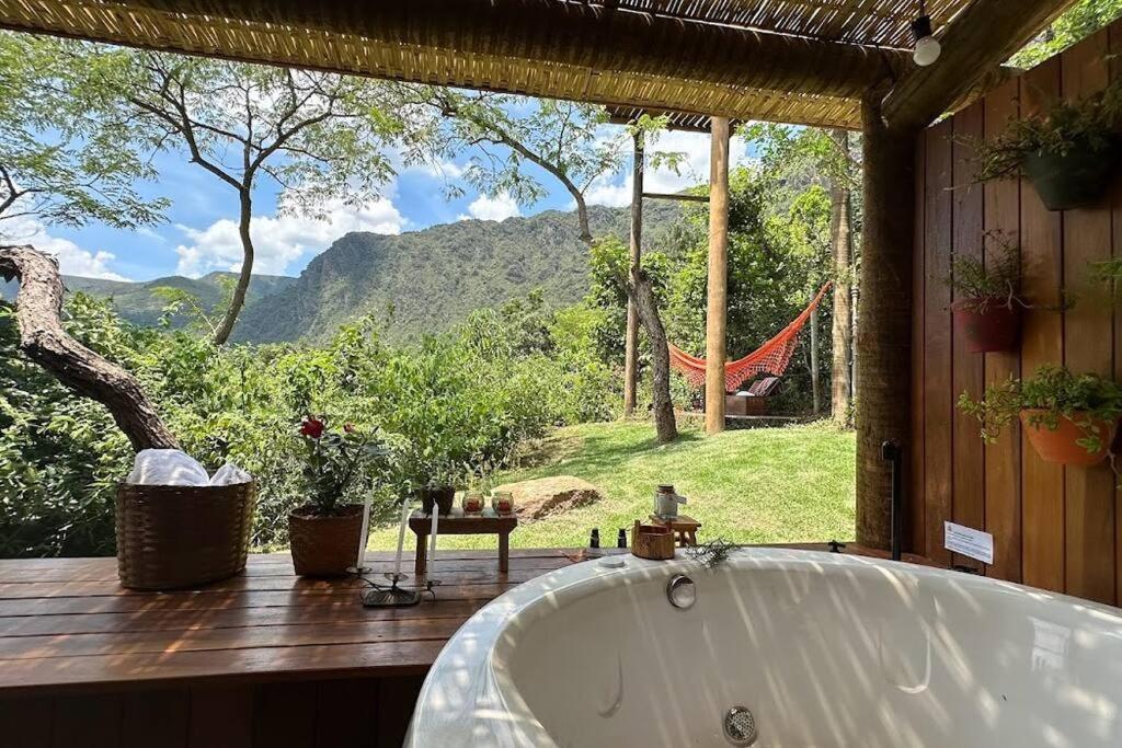 a bath tub in a room with a view of a hammock at Cabanas da Mata - Cabana Flamboyant - Casa Branca in Brumadinho