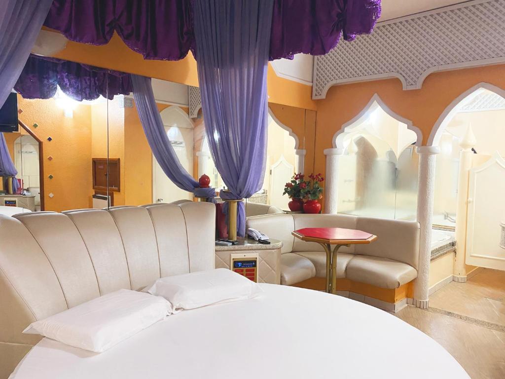 a bedroom with a white bed and purple curtains at Baviera Motel by Drops in Genuino Sampaio