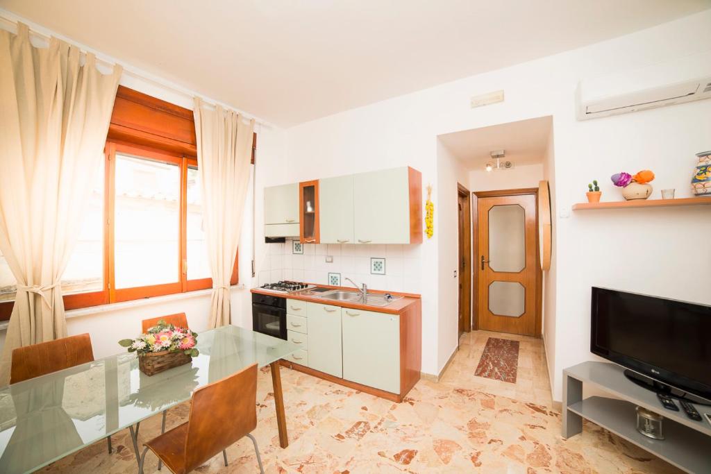 een keuken met een glazen tafel en een televisie bij Le Case della Costa - Appartamento Ravello in Maiori