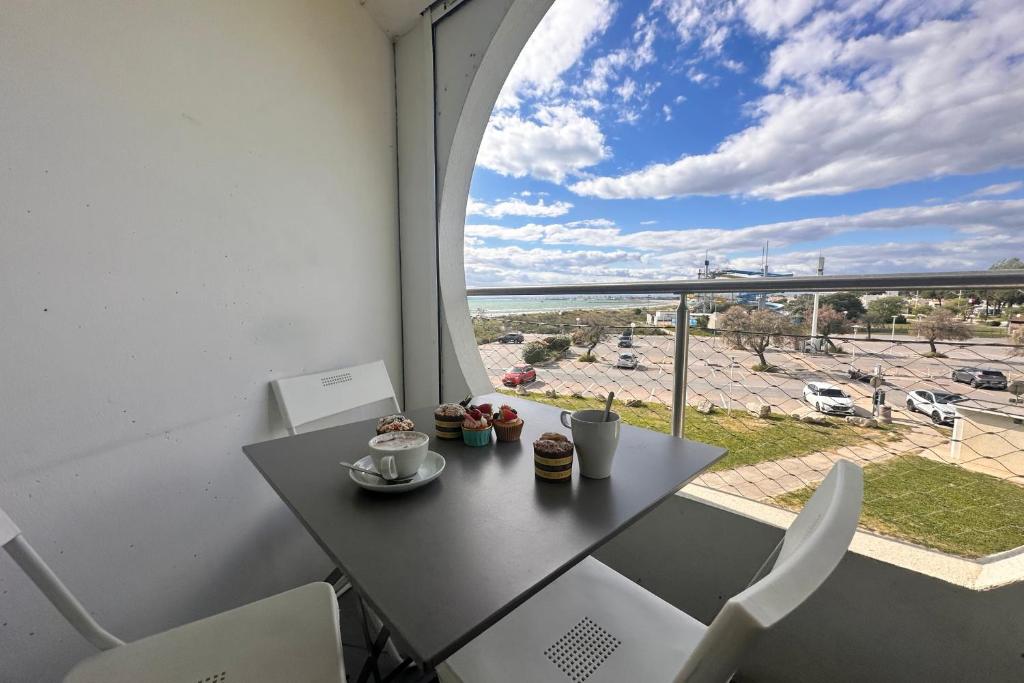 une table et des chaises dans une pièce avec une fenêtre dans l'établissement Le Soleil Couchant Studio Vue Mer, au Grau-du-Roi