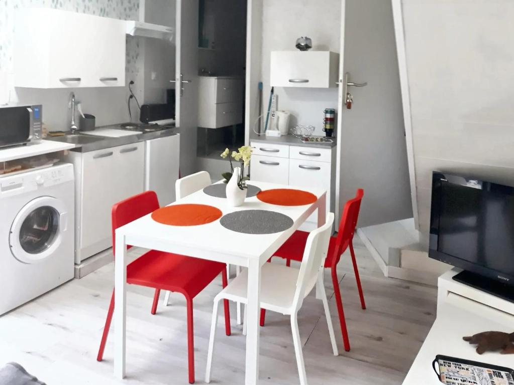 a kitchen with a white table and red chairs at Studio avec piscine partagee jardin clos et wifi a Saint Apollinaire in Saint-Apollinaire