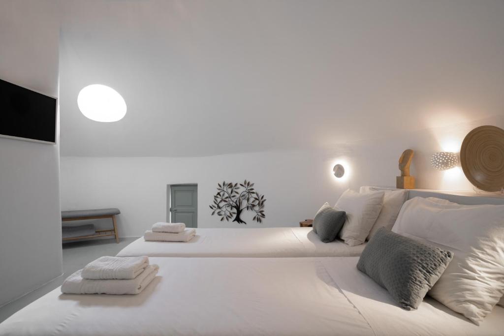 1 dormitorio blanco con 1 cama blanca grande con almohadas en The Sunset Windmill, en Oia