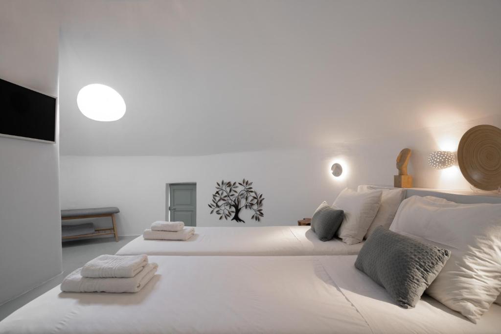 a white bedroom with a large white bed with pillows at The Sunset Windmill in Oia