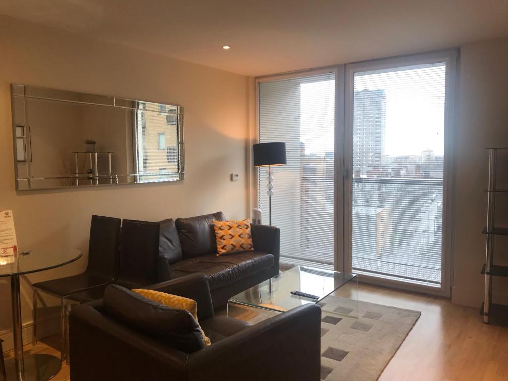 a living room with a leather couch and a large window at Canary Wharf Serviced Apartments in London
